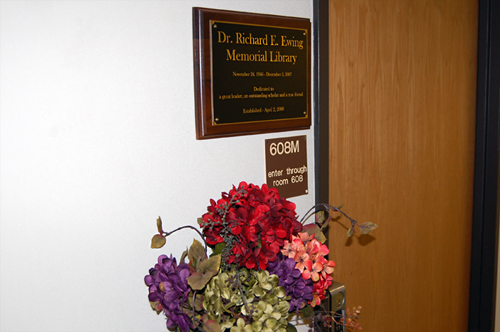 A photograph of the commemorative plaque and the door leading to the Dr. Richard E. Ewing Memorial Library.